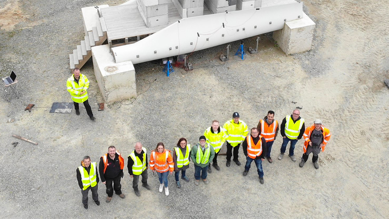 The ReWind team stand in front of a reused wind turbine blade.