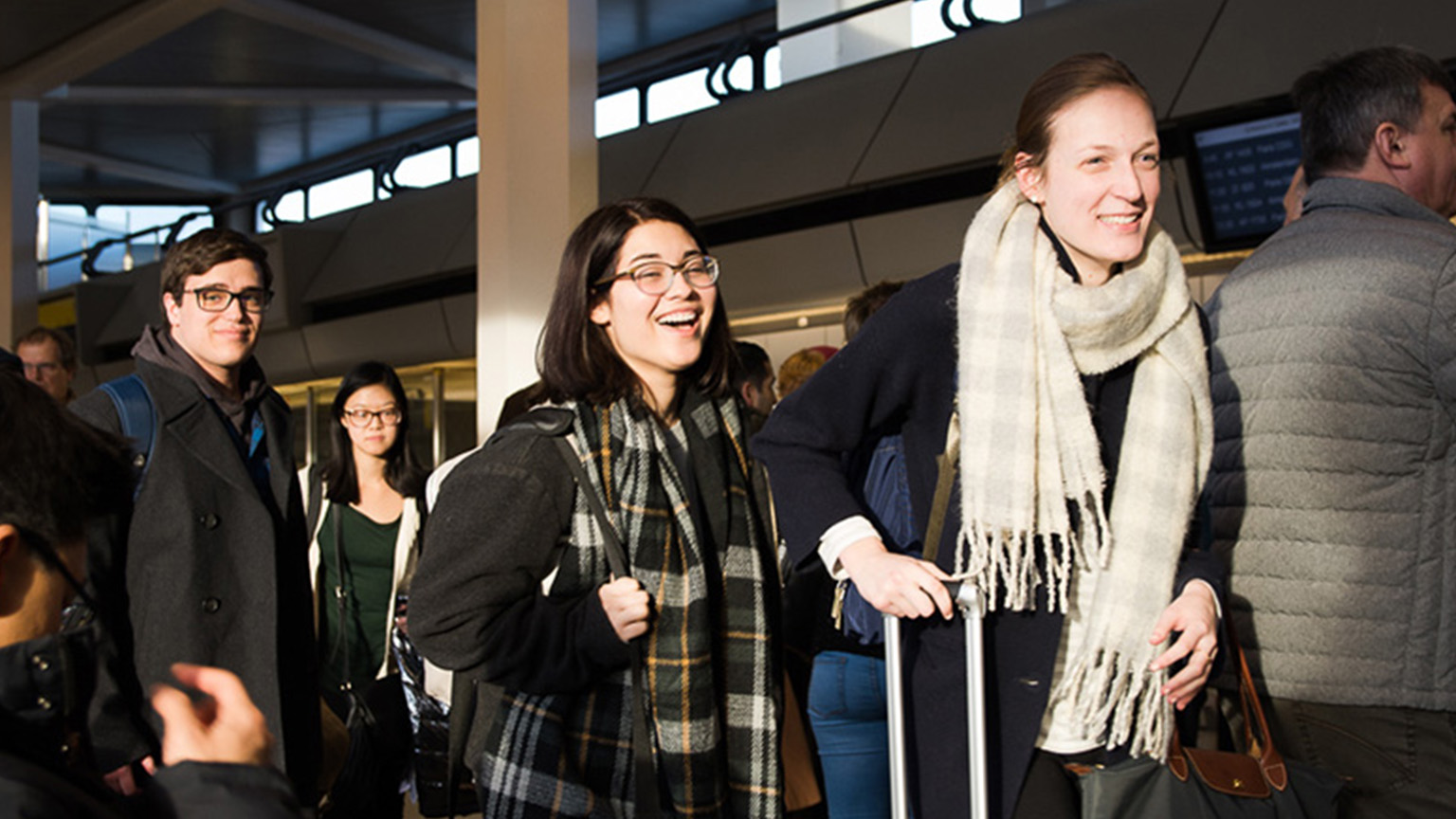 Students walking with their suitcases in an airport ready to begin their international education experience.