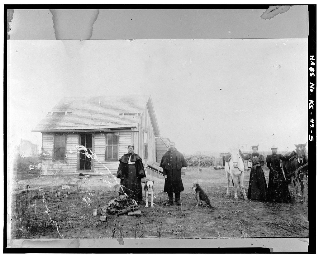 Archival photo of African Americans standing in front of a home in Nicodemus after the Civil War
